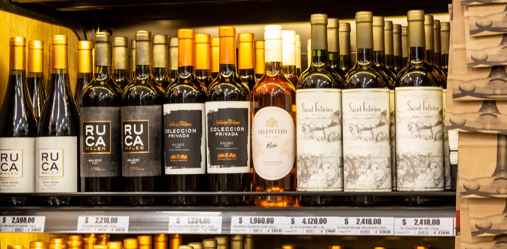 Góndola de bodega con botellas de vino organizadas en estantes comerciales con portaprecios