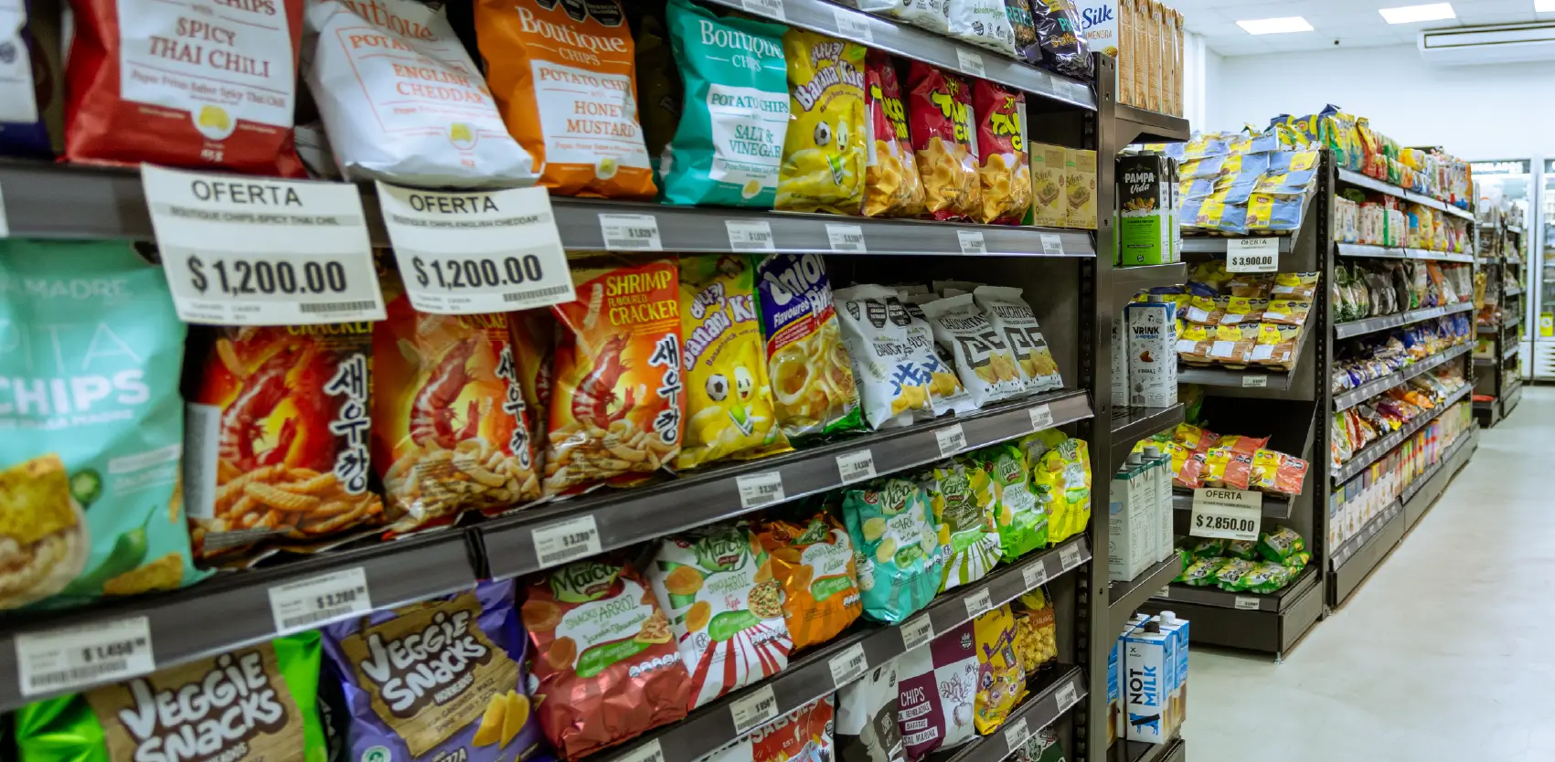 Góndolas de supermercado con exhibición organizada de snacks y productos de consumo masivo en pasillo comercial
